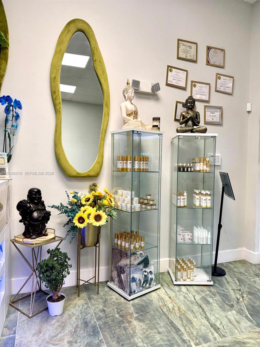 This spa interior features two glass display cases, a decorative mirror, and wall-mounted framed certificates — 18710 SW 107 ave, Miami FL 33157, MIAMI, FL