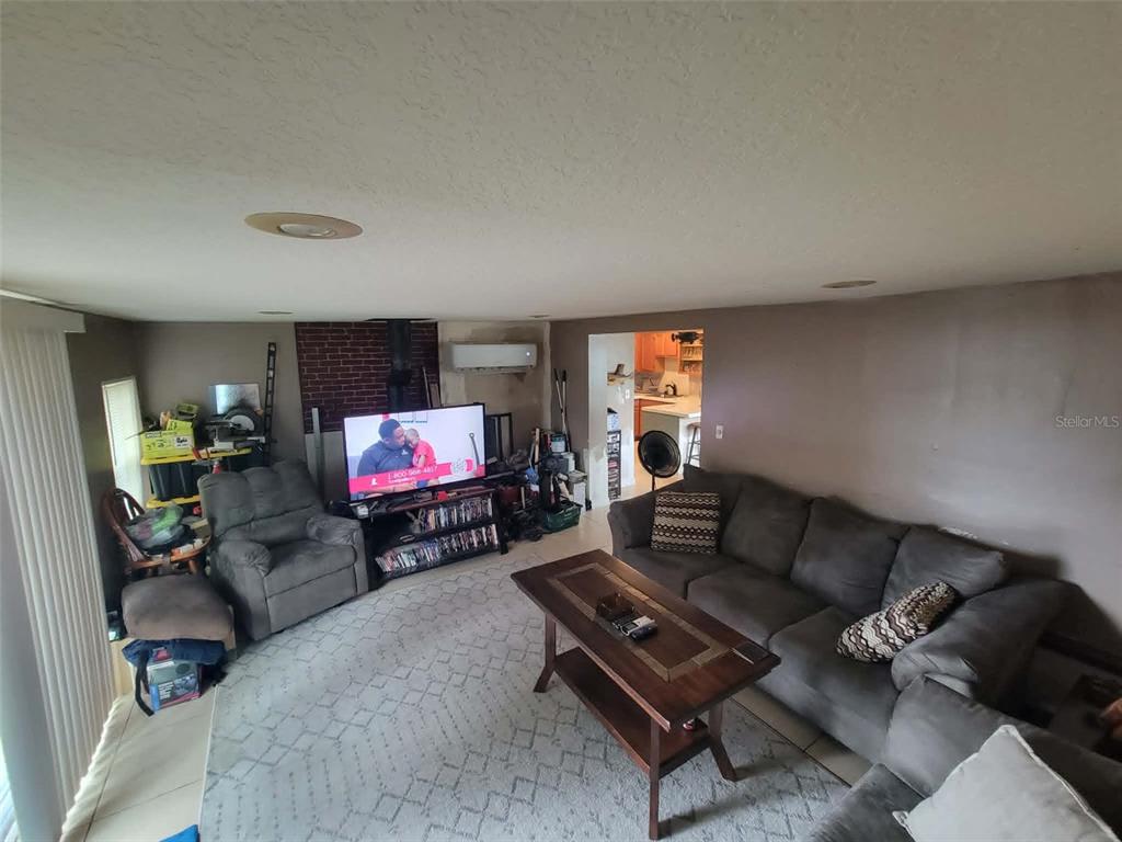 A living room features a grey sectional sofa, a television on a stand, and tile flooring — 8446 WAVERLY ROAD N, ST PETERSBURG, FL