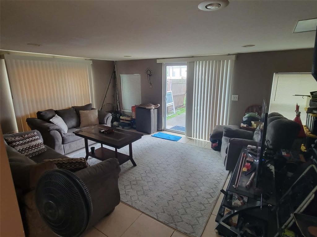 A living room with tile floors, a large area rug, two sofas, and sliding glass doors — 8446 WAVERLY ROAD N, ST PETERSBURG, FL