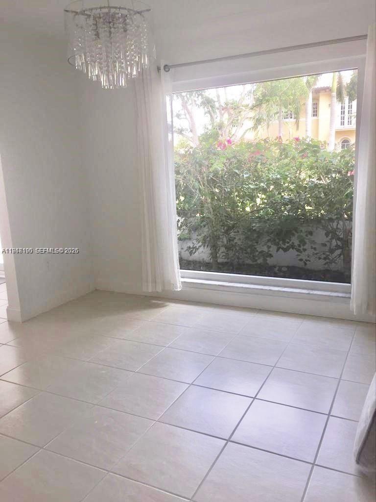 A bright room features light-colored tile flooring, white walls, and a set of French doors — 1460 Tagus Ave, Coral Gables FL 33156, CORAL GABLES, FL