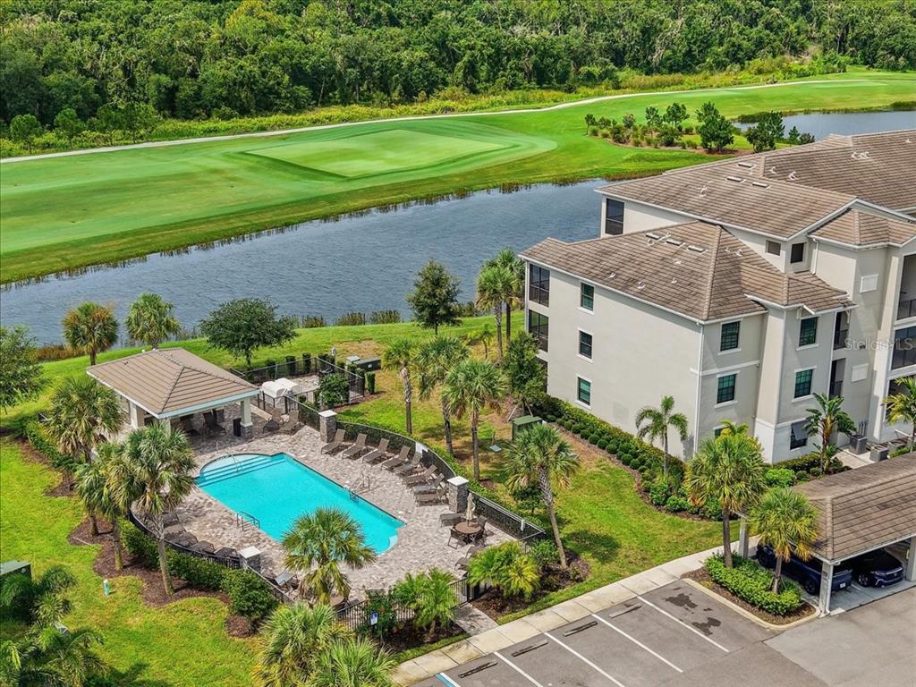 An aerial view of a swimming pool, a multi-story apartment building, and a golf course — 17520 GAWTHROP DRIVE UNIT 305, LAKEWOOD RANCH, FL