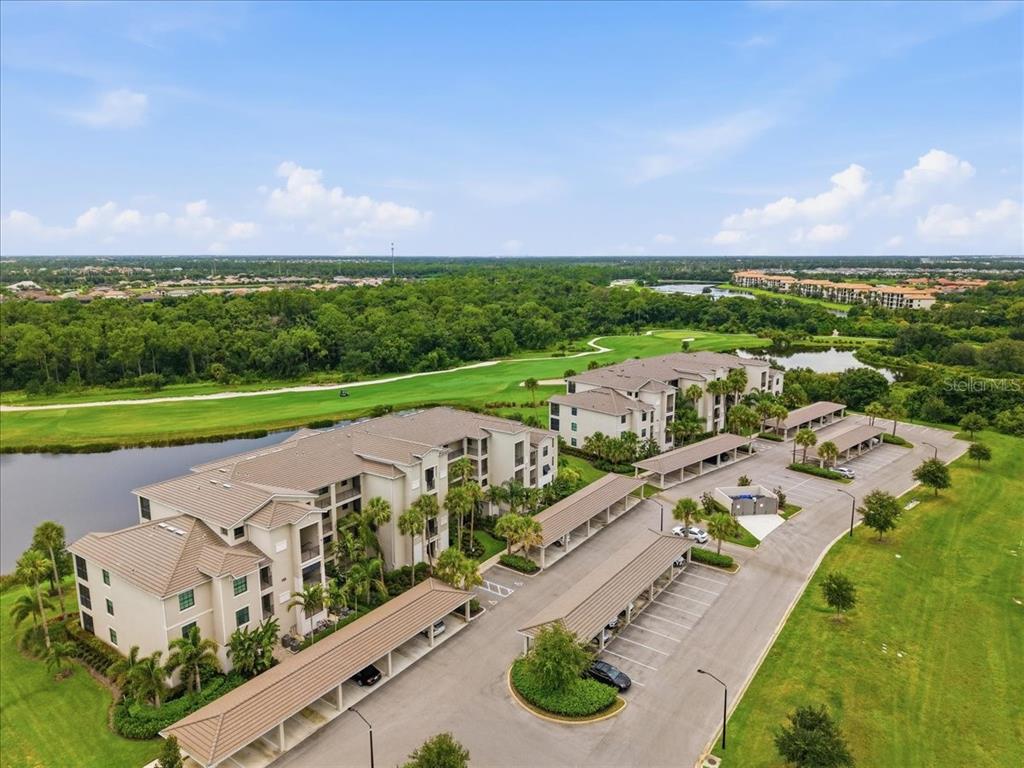 An aerial view shows two multi-story apartment buildings with covered parking lots and a golf course — 17520 GAWTHROP DRIVE UNIT 305, LAKEWOOD RANCH, FL