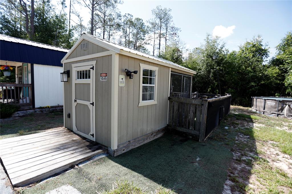 A tan shed with a wooden deck and an attached outdoor dog kennel area — 9060 KINDLEWOOD TRAIL, BROOKSVILLE, FL