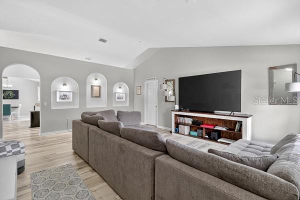 A living room features a large sectional sofa, a television console, and arched wall niches — 3857 SLEEPY HILL OAKS LOOP, LAKELAND, FL