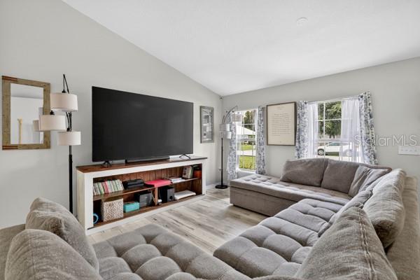 A living room features a large television on a wooden console and a grey sectional — 3857 SLEEPY HILL OAKS LOOP, LAKELAND, FL