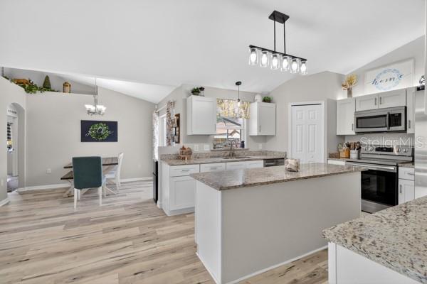 A kitchen with white cabinets, granite countertops, and a dining area with wood-look flooring — 3857 SLEEPY HILL OAKS LOOP, LAKELAND, FL