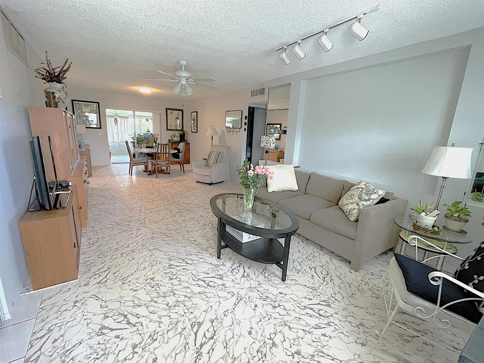 A living and dining area features white marble-patterned flooring, a beige sofa, and track lighting — 2431 Del Aire Boulevard # d, Delray Beach FL 33445, DELRAY BEACH, FL