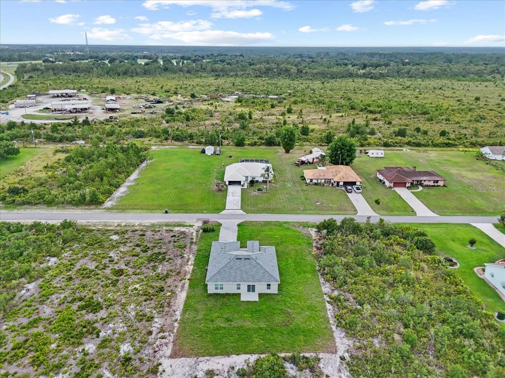 An aerial view shows a single-family home with a driveway surrounded by undeveloped land — 2120 POINCIANA DRIVE, INDIAN LAKE ESTATES, FL