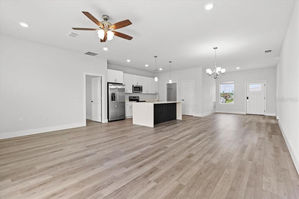 A bright, open-concept kitchen and living area features white cabinetry, a kitchen island, and wood-look flooring — 2120 POINCIANA DRIVE, INDIAN LAKE ESTATES, FL