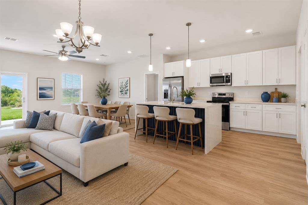 An open-concept kitchen and living area with white cabinetry, a kitchen island, and wood flooring — 2120 POINCIANA DRIVE, INDIAN LAKE ESTATES, FL