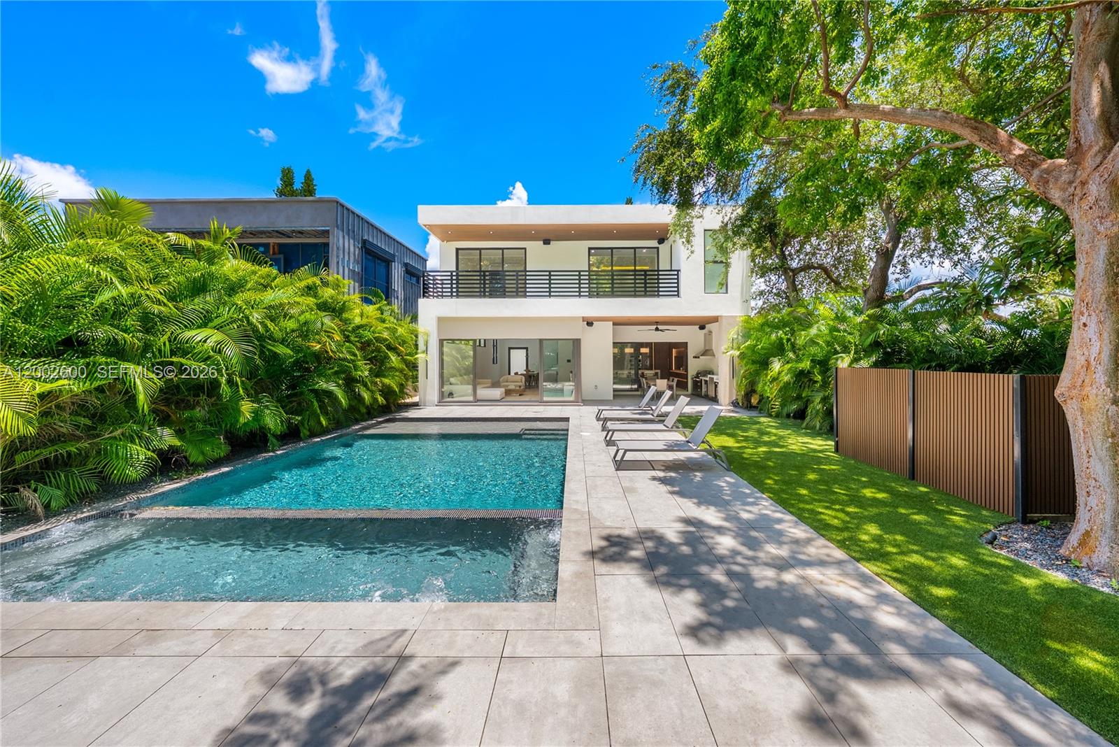 A modern two-story house features a swimming pool, patio, and lush landscaping in the backyard — 260 NW 47th St, Miami FL 33127, MIAMI, FL