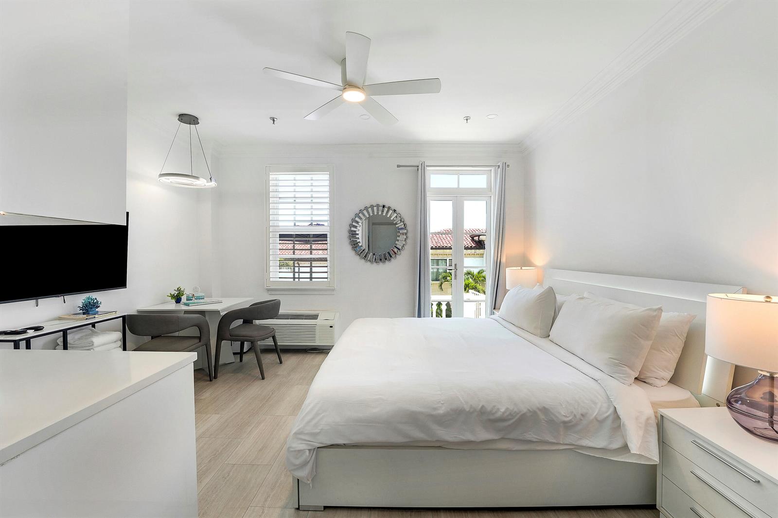 A bedroom features a white bed, a small dining area, and a balcony door — 235 Sunrise Avenue # 2011, Palm Beach FL 33480, PALM BEACH, FL