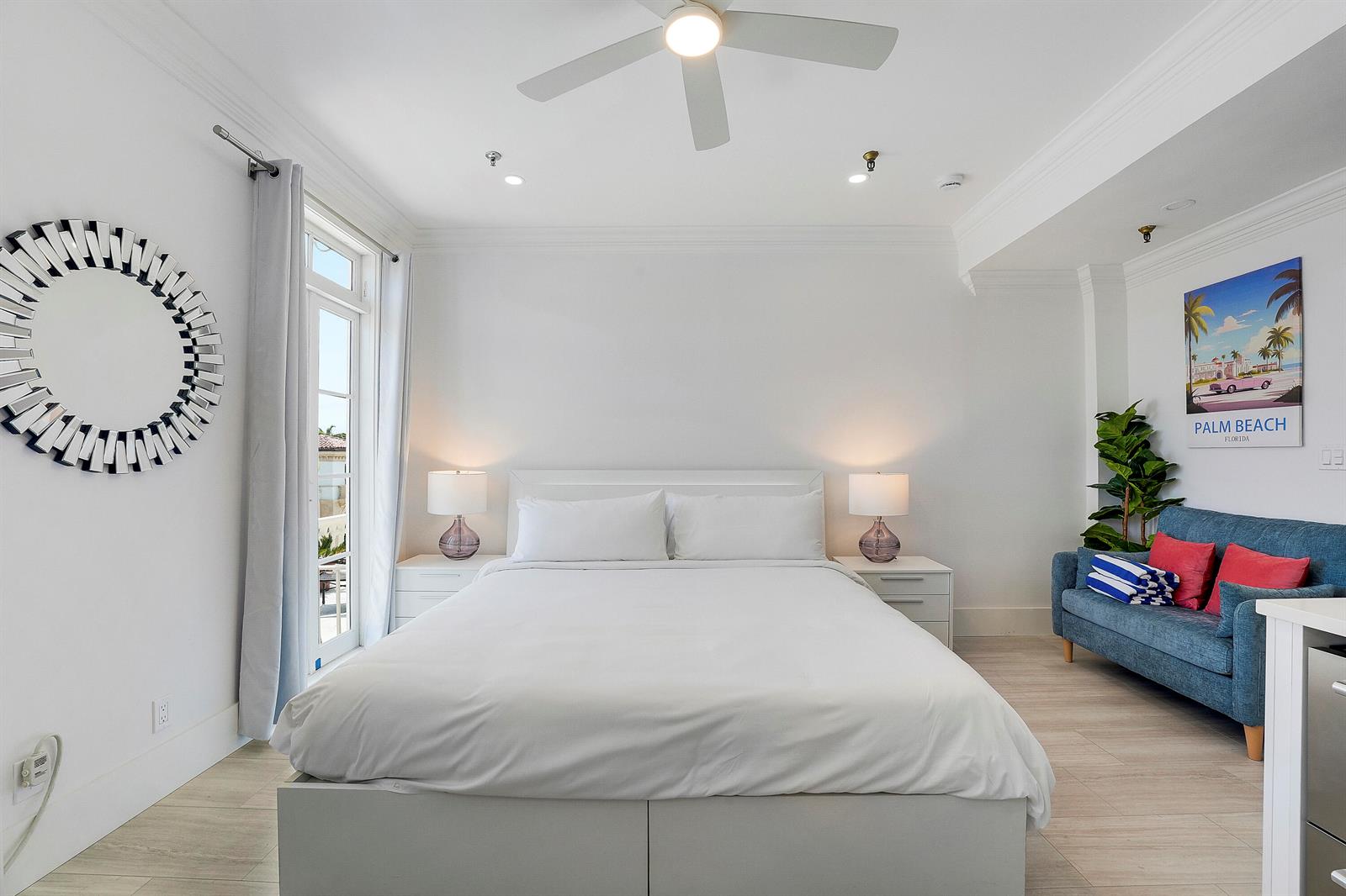 A bedroom features a white bed, two nightstands with lamps, a blue sofa, and a mirror — 235 Sunrise Avenue # 2011, Palm Beach FL 33480, PALM BEACH, FL