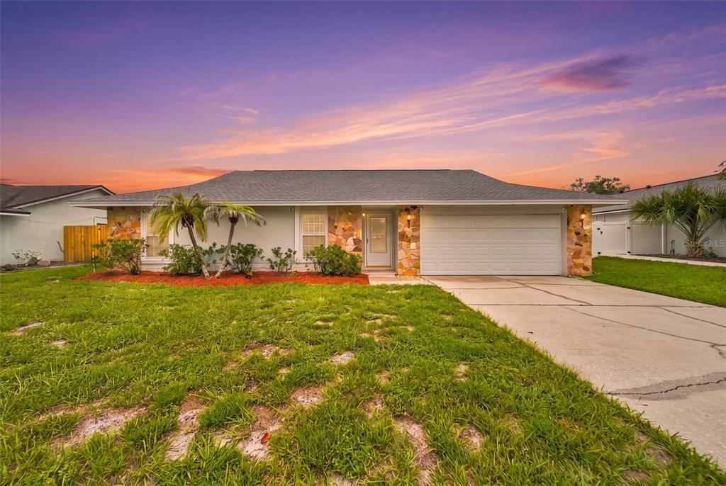 A single-story house with a stone facade, a two-car garage, and a grassy front yard — 1003 WHEELER PLACE, OVIEDO, FL