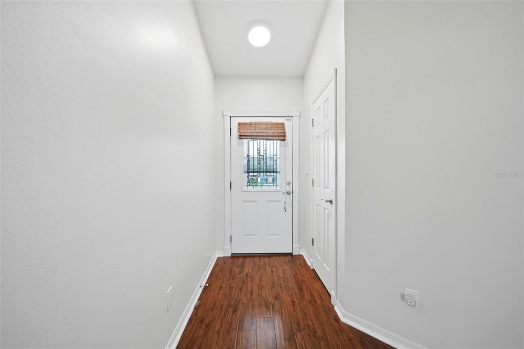 A narrow entryway features white walls, dark wood-look flooring, a white door, and a ceiling light — 1003 WHEELER PLACE, OVIEDO, FL