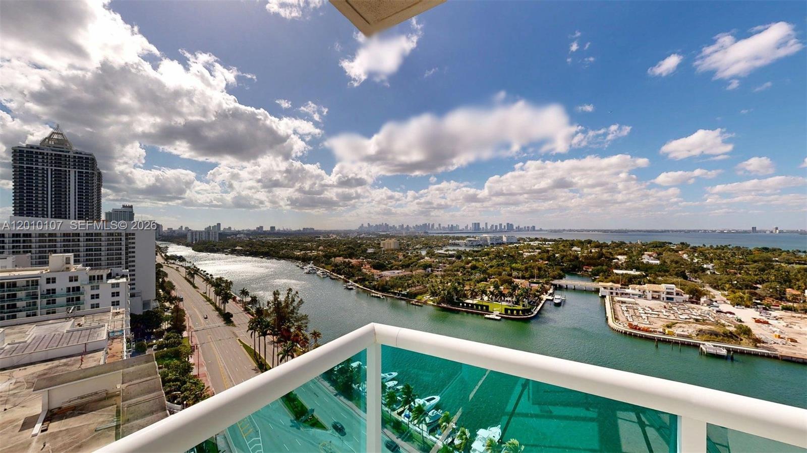 A high-angle view from a balcony overlooking a waterway, road, and city skyline — 5025 Collins Ave # 2206, Miami Beach FL 33140, MIAMI BEACH, FL