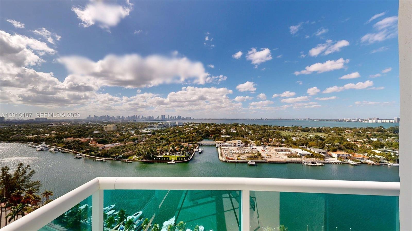 A high-angle view from a balcony overlooking a waterway, residential properties, and a distant skyline — 5025 Collins Ave # 2206, Miami Beach FL 33140, MIAMI BEACH, FL