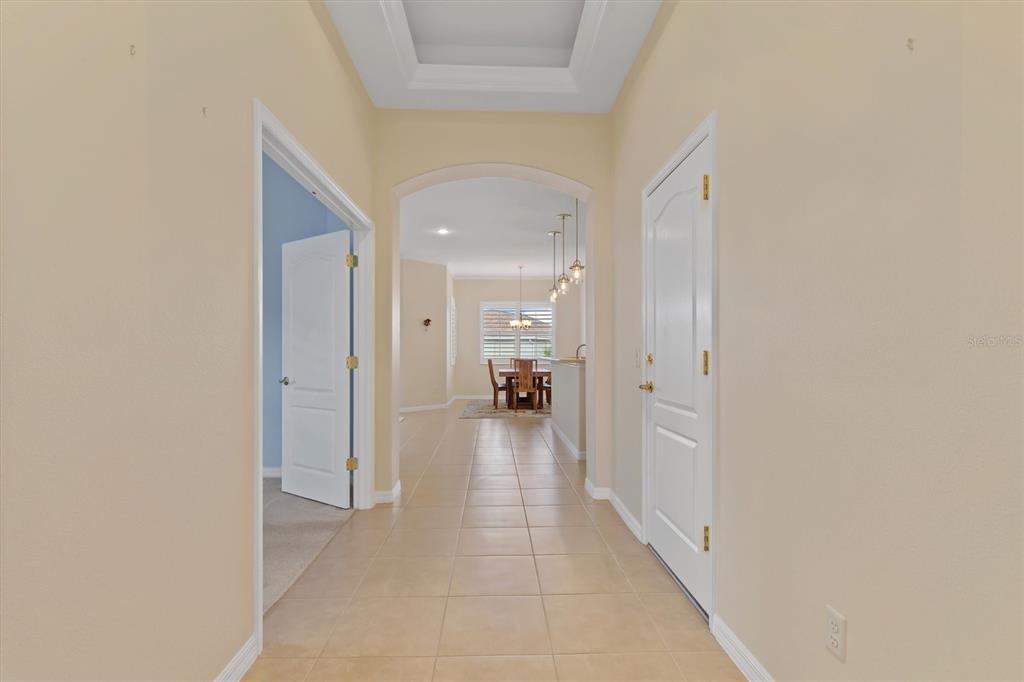 A tiled hallway leads toward a dining area with a tray ceiling and arched entryway — 1837 KNIGHTS BRIDGE TRAIL, PUNTA GORDA, FL