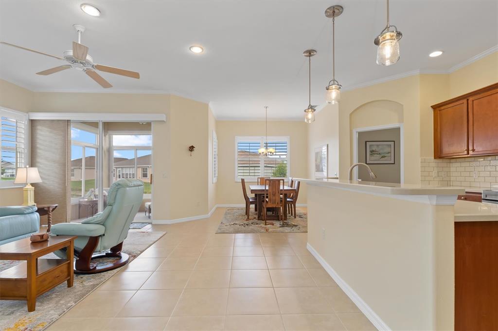 An open-concept living and dining area features tile flooring, a ceiling fan, and pendant lighting — 1837 KNIGHTS BRIDGE TRAIL, PUNTA GORDA, FL
