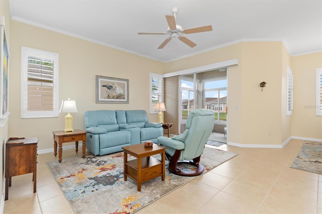 A living room features a blue sofa and recliner on a patterned rug with tile flooring — 1837 KNIGHTS BRIDGE TRAIL, PUNTA GORDA, FL