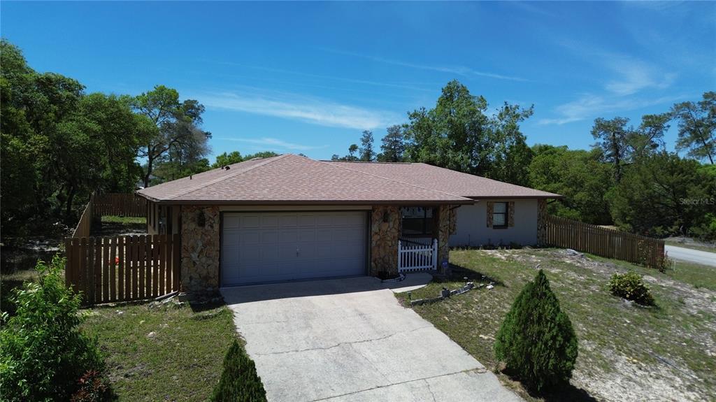 A single-story house with a stone facade, a two-car garage, and a wooden fence — 16920 SW 39TH CIRCLE, OCALA, FL