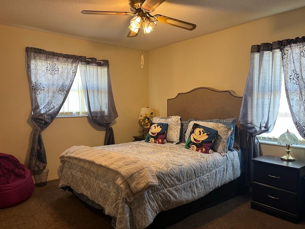 A bedroom features a bed with Mickey Mouse pillows, a ceiling fan, and two windows — 16920 SW 39TH CIRCLE, OCALA, FL