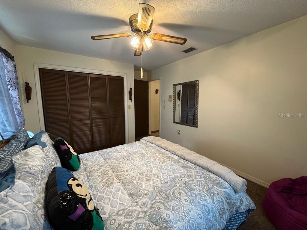 A bedroom features a ceiling fan, a bed with patterned bedding, and louvered closet doors — 16920 SW 39TH CIRCLE, OCALA, FL