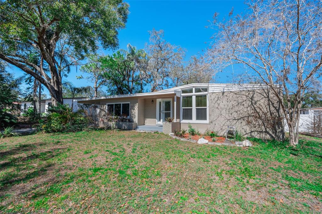 A single-story house with a flat roof, brick facade, and large windows sits on grass — 206 LINDA AVENUE, TEMPLE TERRACE, FL