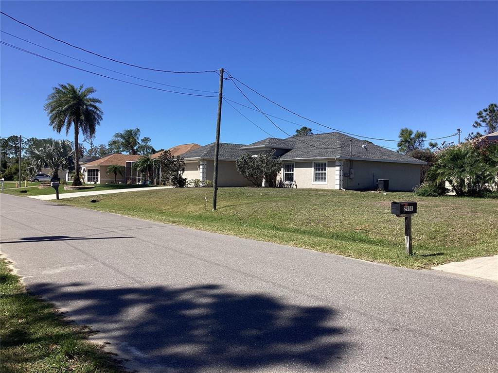 A single-story house with a gray shingled roof sits on a grassy lot near a street — BELLEVILLE TERRACE, NORTH PORT, FL