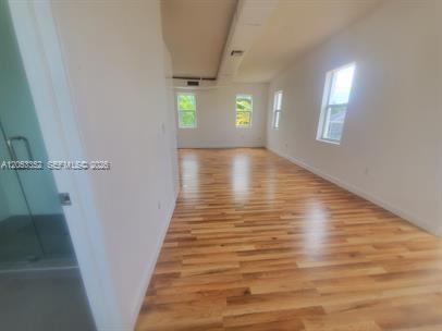 An interior view of a room with hardwood floors, white walls, and several windows — 101 SE 2nd St # 2, Dania Beach FL 33004, DANIA BEACH, FL
