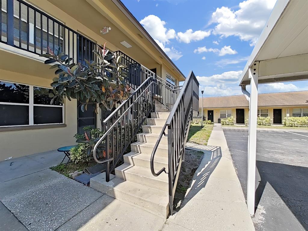 An exterior view of a two-story apartment building with a concrete staircase and metal railings — 2501 HARN BOULEVARD UNIT H39, CLEARWATER, FL