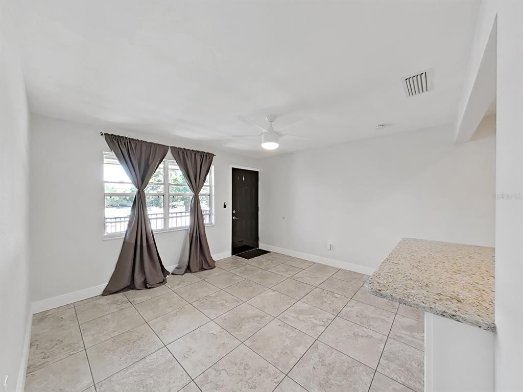A living room with light tile flooring, a ceiling fan, and a dark front door — 2501 HARN BOULEVARD UNIT H39, CLEARWATER, FL