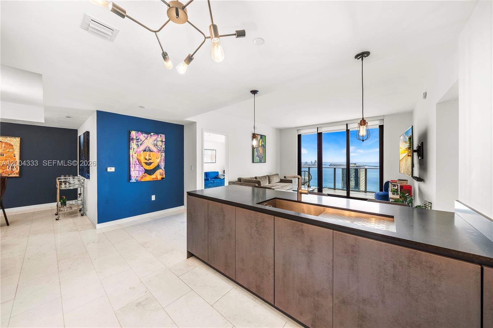 A modern kitchen island with a dark countertop faces a living area with ocean views — 1010 Brickell Ave # 3904, Miami FL 33131, MIAMI, FL