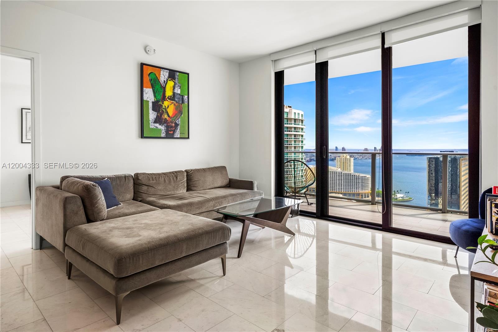 A living room features a grey sectional sofa, glass coffee table, and floor-to-ceiling balcony windows — 1010 Brickell Ave # 3904, Miami FL 33131, MIAMI, FL