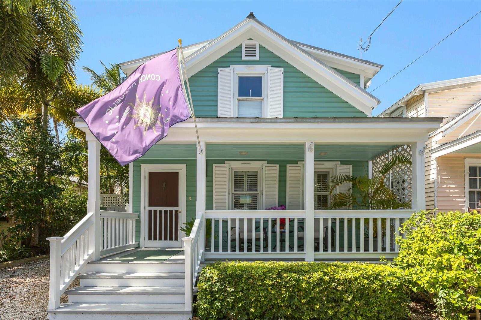 A teal two-story house features a front porch with white railings and a purple flag — 508 Grinnell Street, Key West FL 33040, KEY WEST, FL