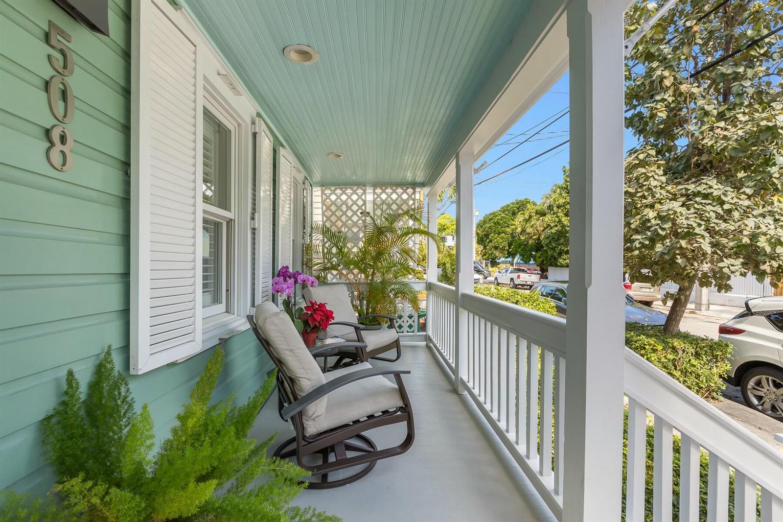 A covered front porch features light green siding, white railings, and two outdoor rocking chairs — 508 Grinnell Street, Key West FL 33040, KEY WEST, FL