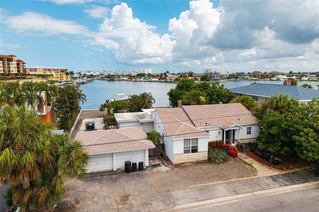 An aerial view shows a single-story house with a two-car garage near a waterfront — 216 PUNTA VISTA DRIVE, ST PETE BEACH, FL