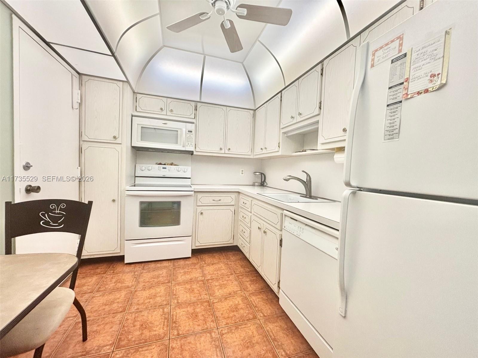 A kitchen features white cabinetry, white appliances, a vaulted ceiling with a fan, and tiled flooring — 1965 S Ocean Dr # 11N, Hallandale Beach FL 33009, HALLANDALE BEACH, FL