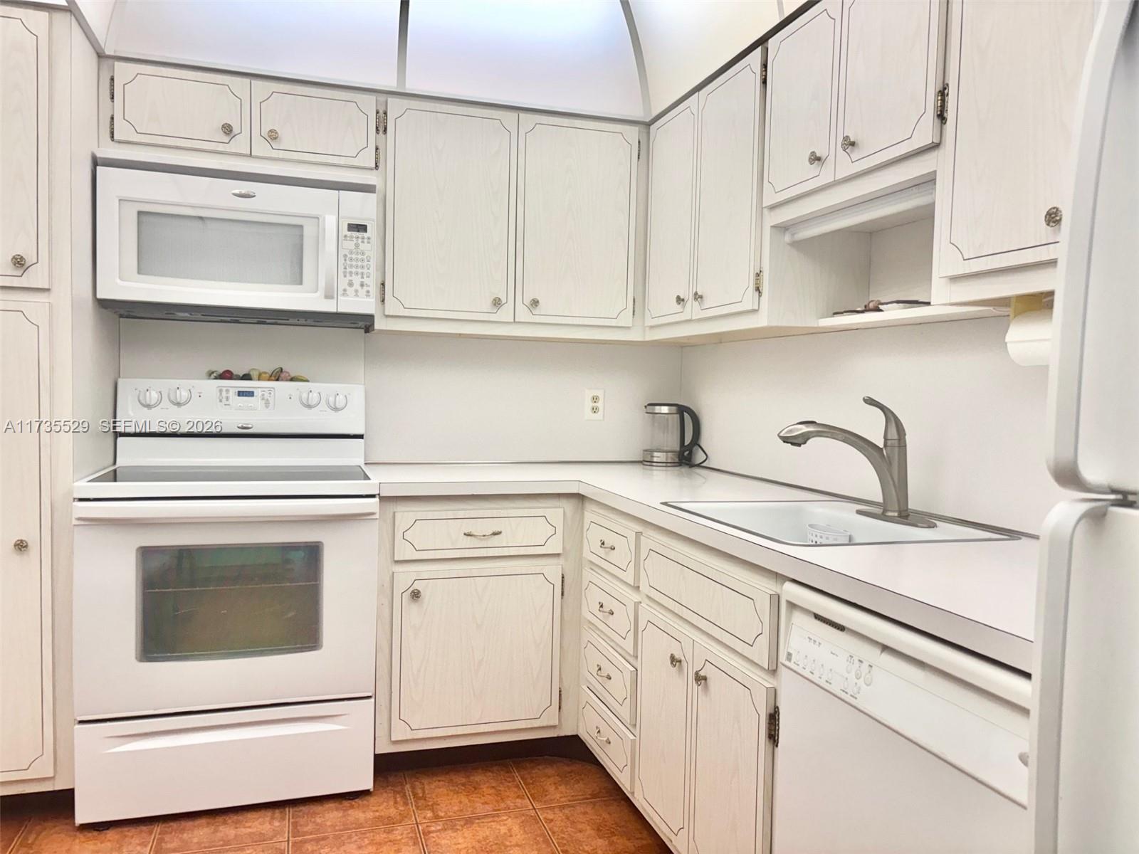 A kitchen features white wood-grain cabinets, white appliances, a stainless steel faucet, and tile flooring — 1965 S Ocean Dr # 11N, Hallandale Beach FL 33009, HALLANDALE BEACH, FL