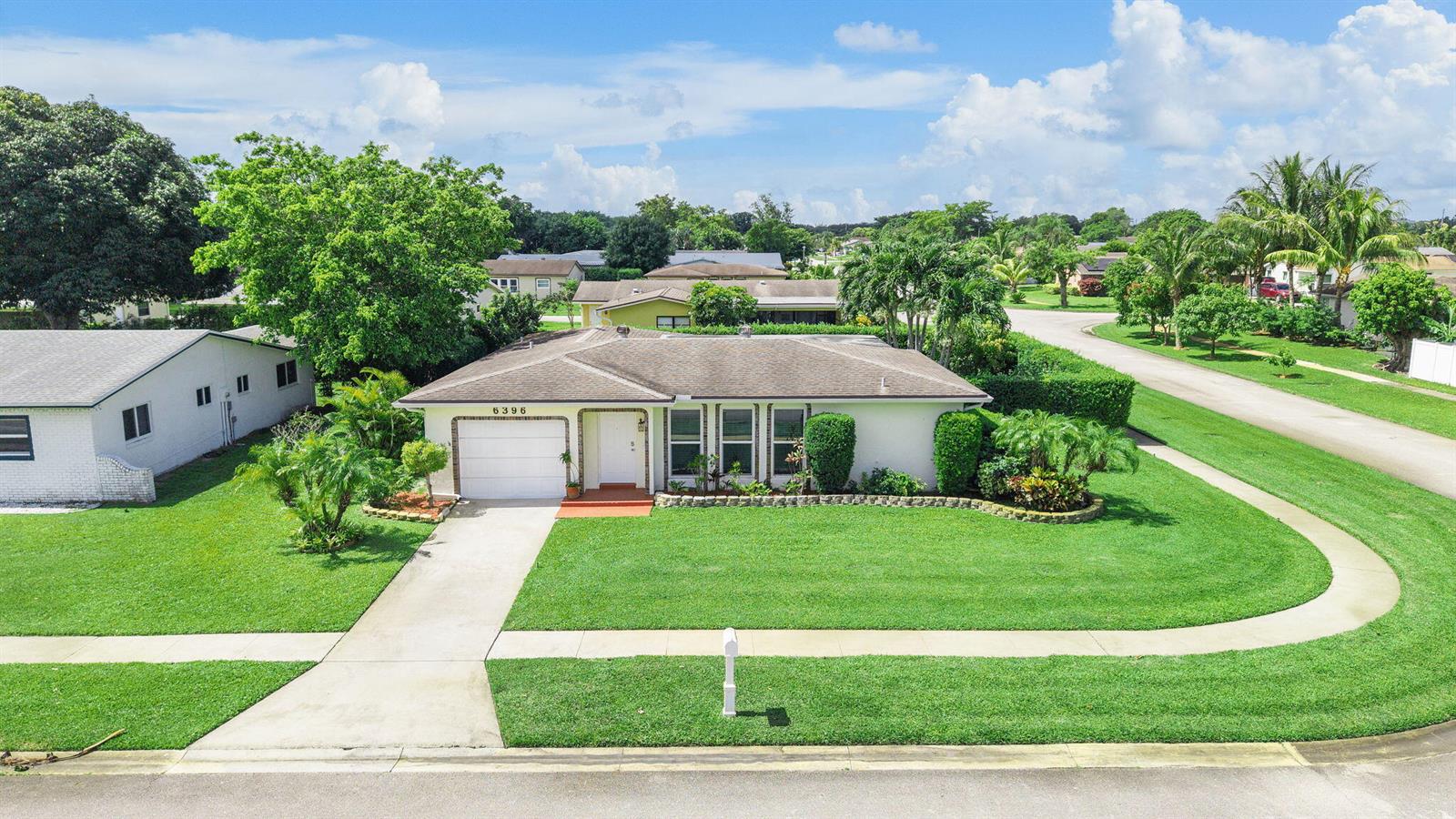 An aerial view shows a single-story house with a white garage and a green lawn — 6396 Whispering Wind Way, Delray Beach FL 33484, DELRAY BEACH, FL