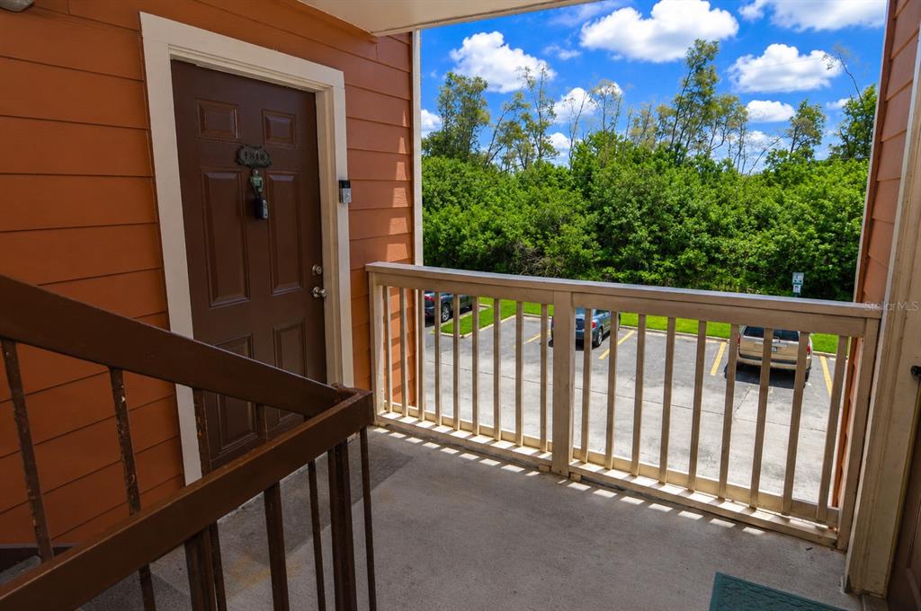 An exterior view of an apartment balcony with a brown door and wooden railings — 10200 GANDY BOULEVARD N UNIT 1313, ST PETERSBURG, FL