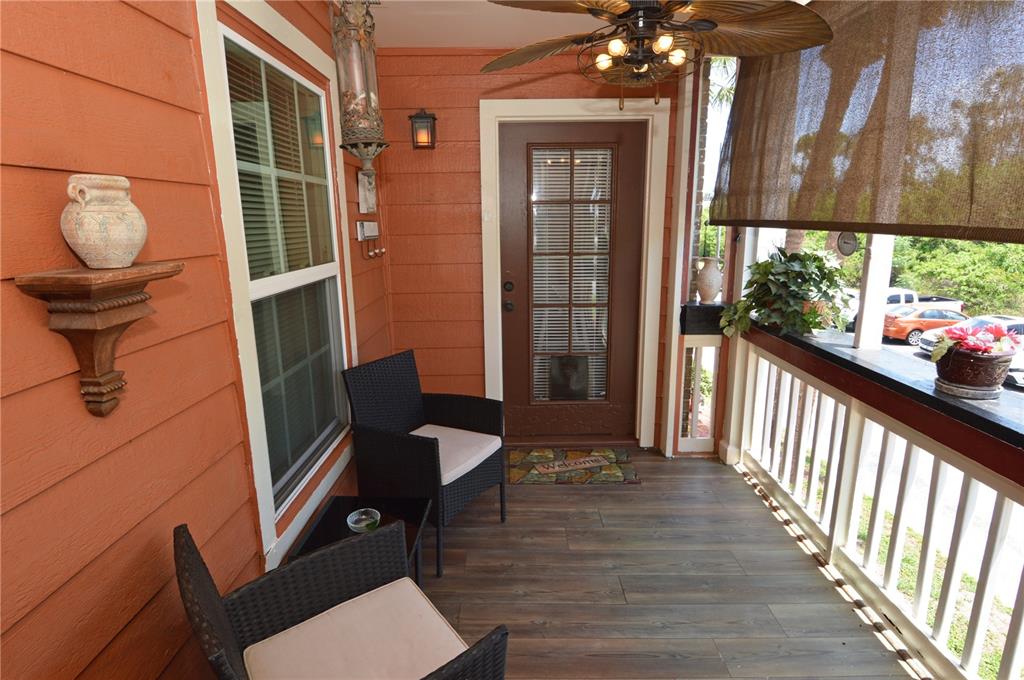 A covered porch features orange siding, a brown door, two wicker chairs, and wood-look flooring — 10200 GANDY BOULEVARD N UNIT 1313, ST PETERSBURG, FL