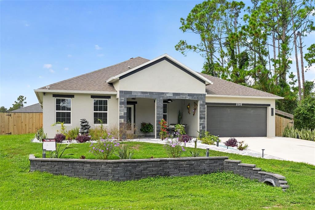 A single-story house with a gray stone facade, a two-car garage, and a landscaped yard — 2595 HAGOPLAN LANE, NORTH PORT, FL