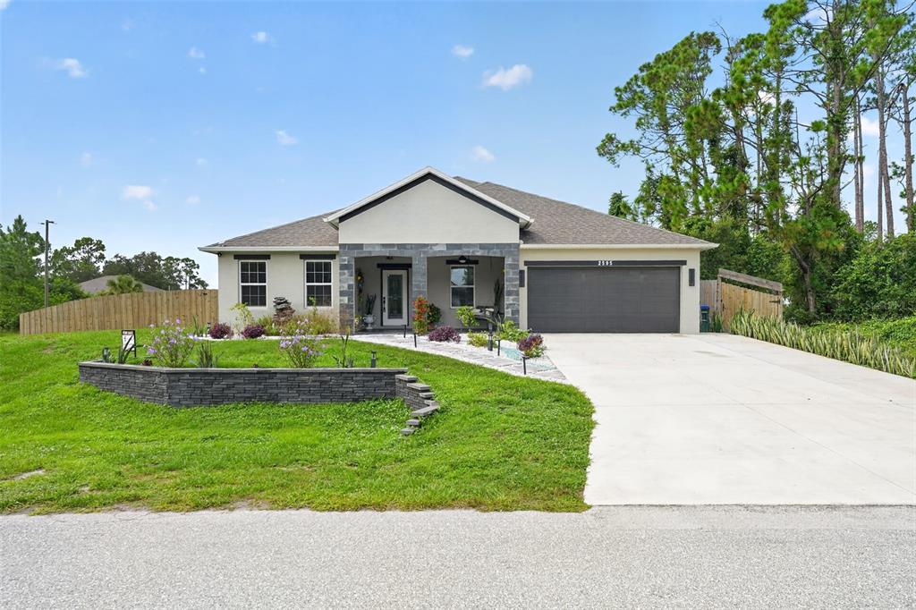 A single-story house with a gray garage, stone accents, and a landscaped front yard — 2595 HAGOPLAN LANE, NORTH PORT, FL