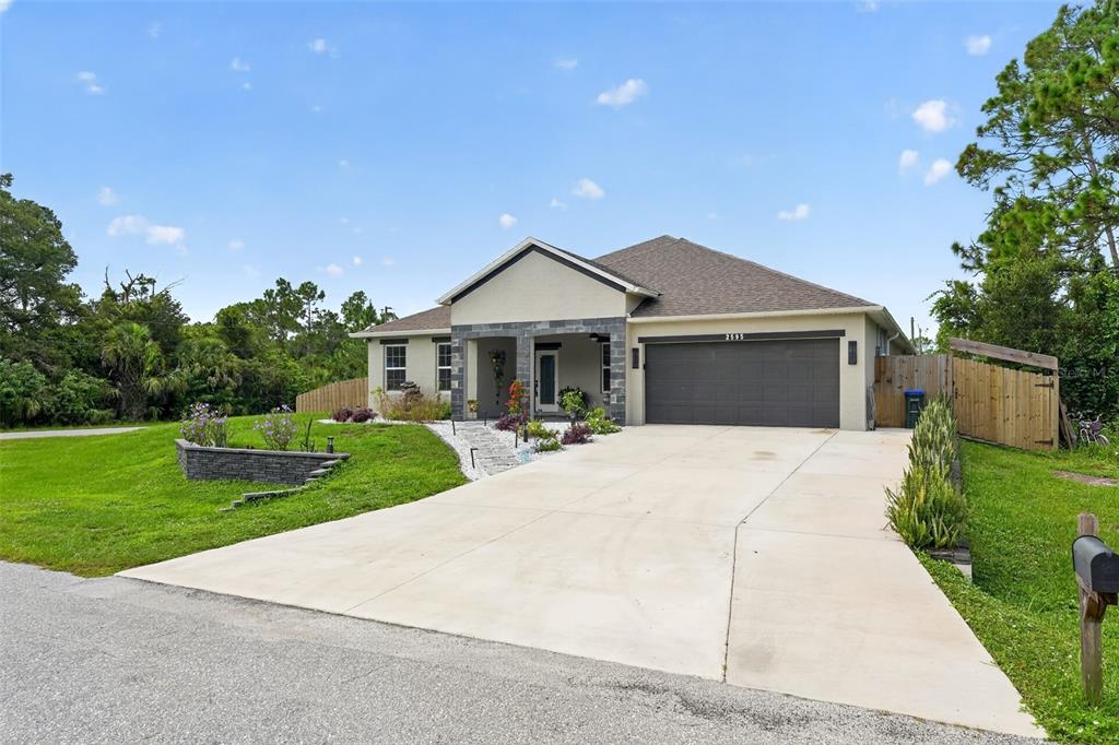 A single-story house with a gray garage, stone accents, and a concrete driveway — 2595 HAGOPLAN LANE, NORTH PORT, FL