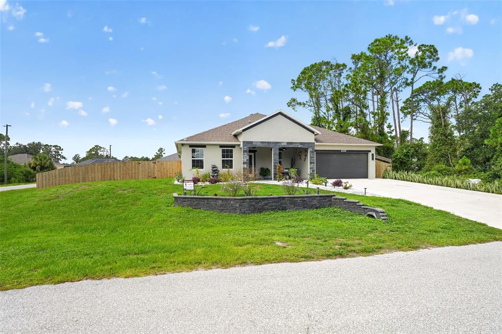 A single-story house with a stone-accented facade, a two-car garage, and a landscaped front yard — 2595 HAGOPLAN LANE, NORTH PORT, FL