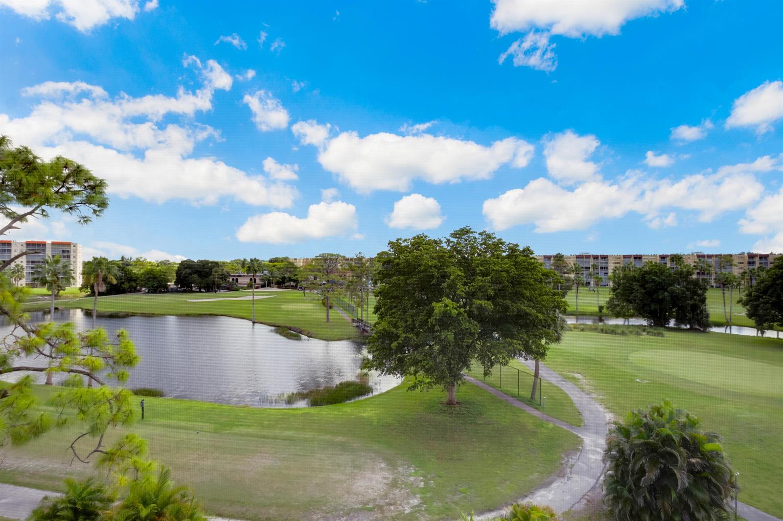 An elevated view of a golf course with a pond, trees, and apartment buildings — 3593 Birdie Drive # 507, Lake Worth FL 33467, LAKE WORTH, FL