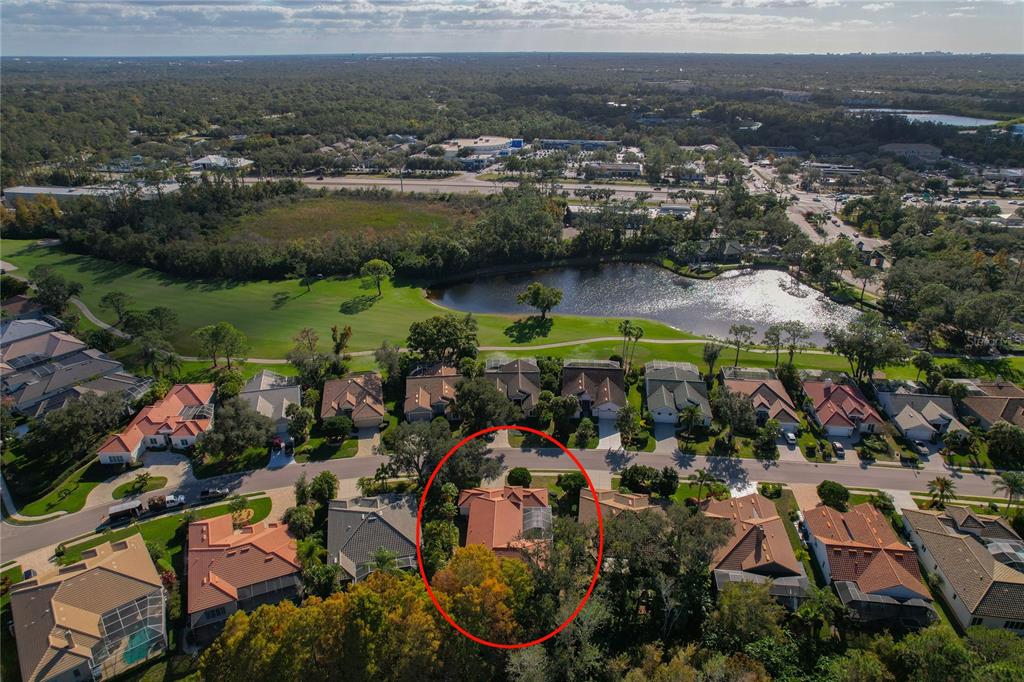 An aerial view shows a residential neighborhood with a red-roofed house circled in red — 8717 54TH AVENUE E UNIT NA, BRADENTON, FL