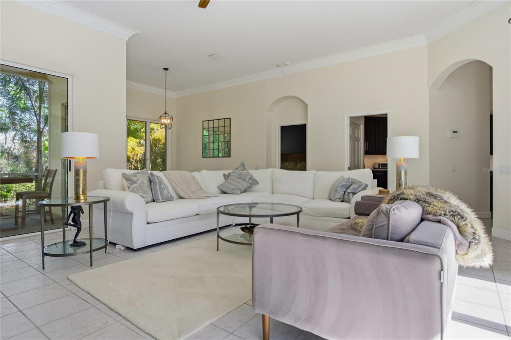 A living room features a white sectional sofa, a glass coffee table, and tile flooring — 8717 54TH AVENUE E UNIT NA, BRADENTON, FL