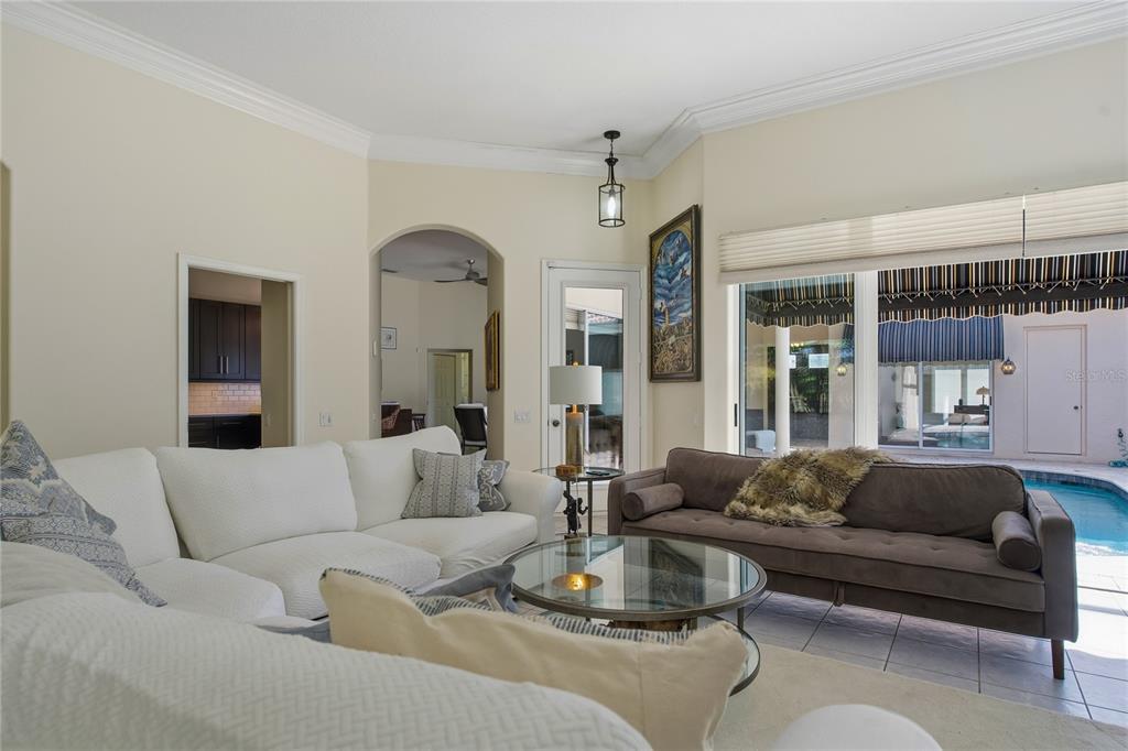 A living room features a white sectional, a brown sofa, and a view of a pool — 8717 54TH AVENUE E UNIT NA, BRADENTON, FL